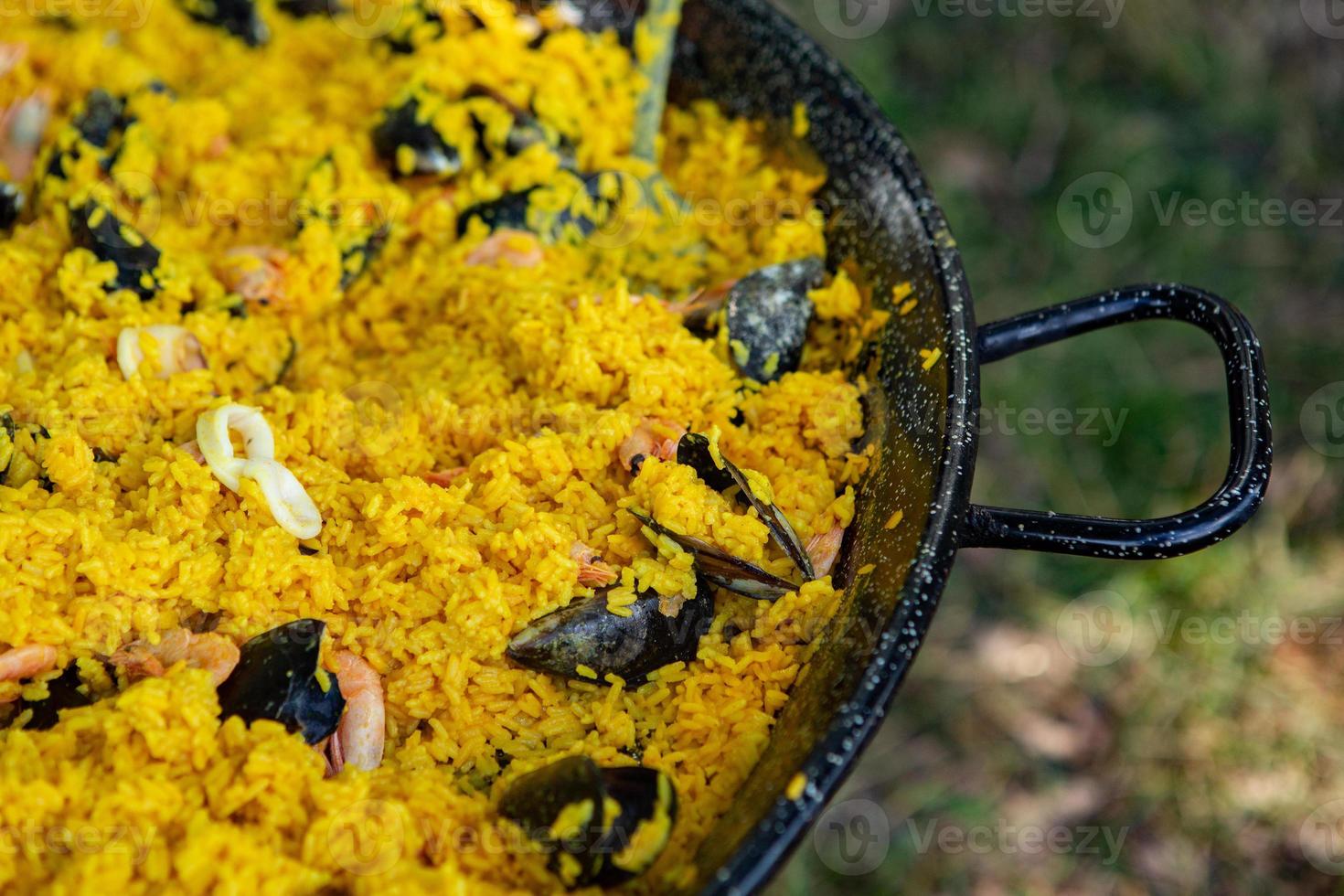 paella traditionelles spanisches essen. Paella zubereitet auf einer großen Pfanne auf der Straße in Flammen foto