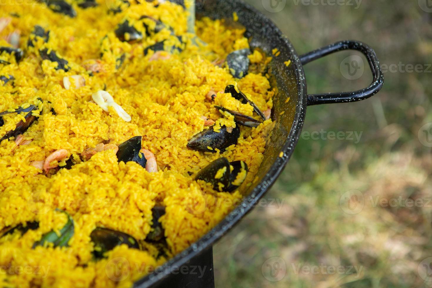 paella traditionelles spanisches essen. Paella zubereitet auf einer großen Pfanne auf der Straße in Flammen foto