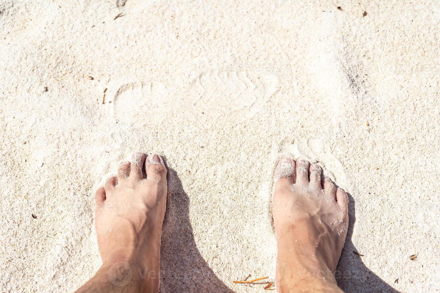2 Füße auf dem Bleichmittel. Nahaufnahme eines jungen Mannes Füße an einem tropischen Sandstrand. foto