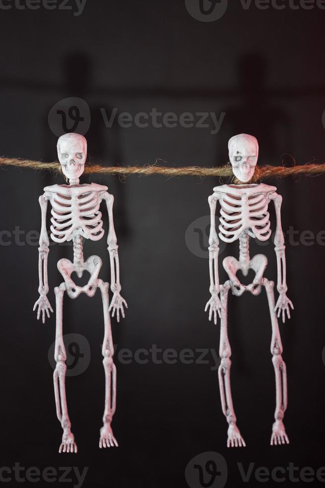 Skelette hängen an einem Seil auf schwarzem Hintergrund mit roter Beleuchtung foto