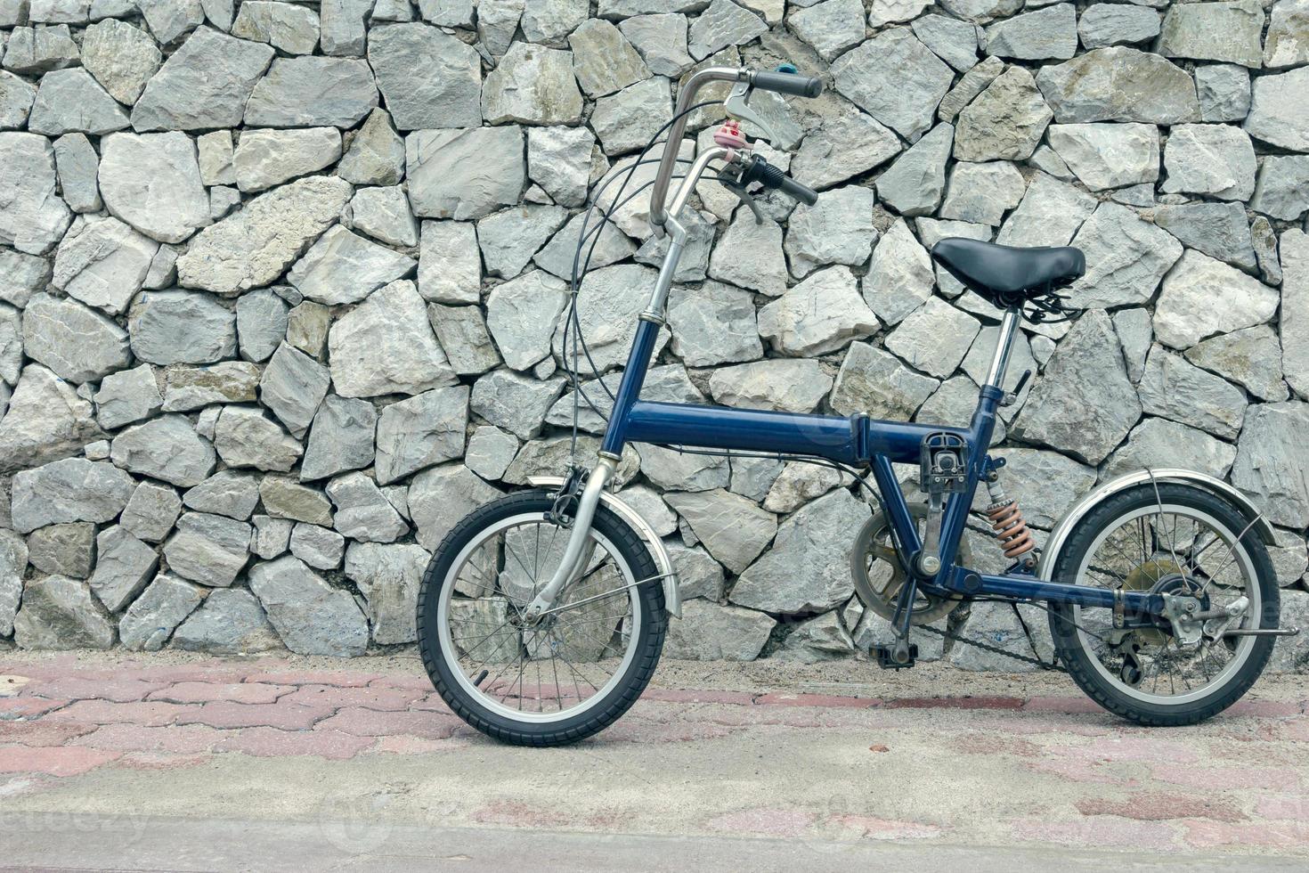blaues Fahrrad mit Steinhintergrund, Vintage-Effektfilter foto