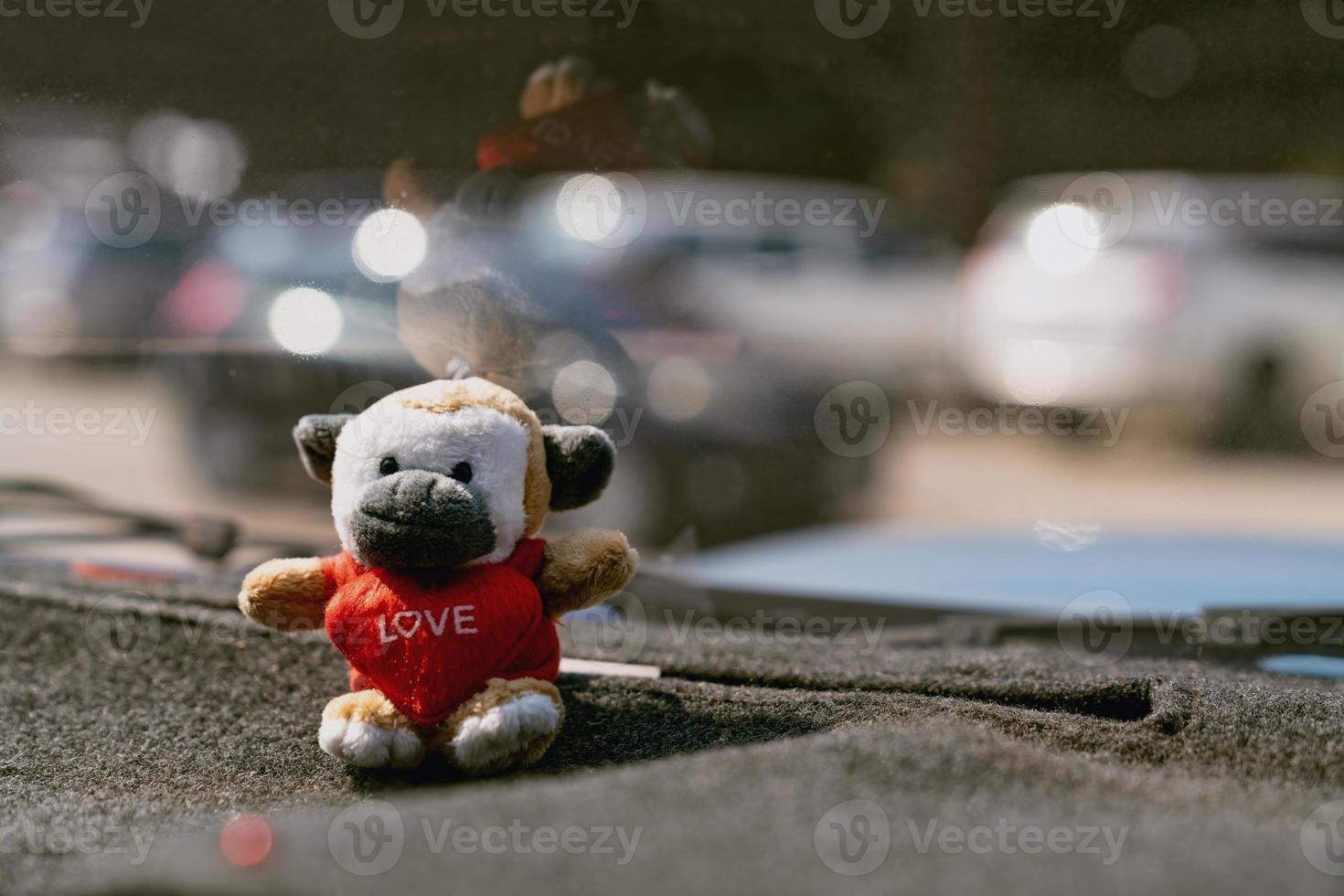Kuhpuppe und rotes Herz auf der Konsole des Autos mit Bokeh-Hintergrund foto