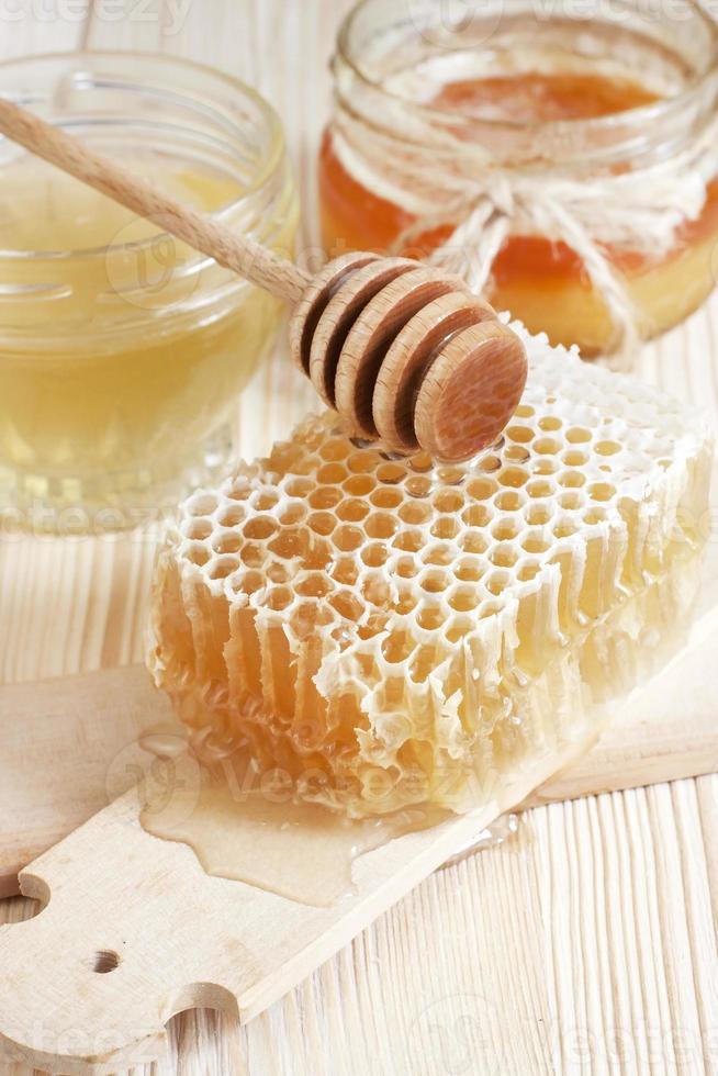 Honig im Glas mit Wabe und Holzlöffel foto