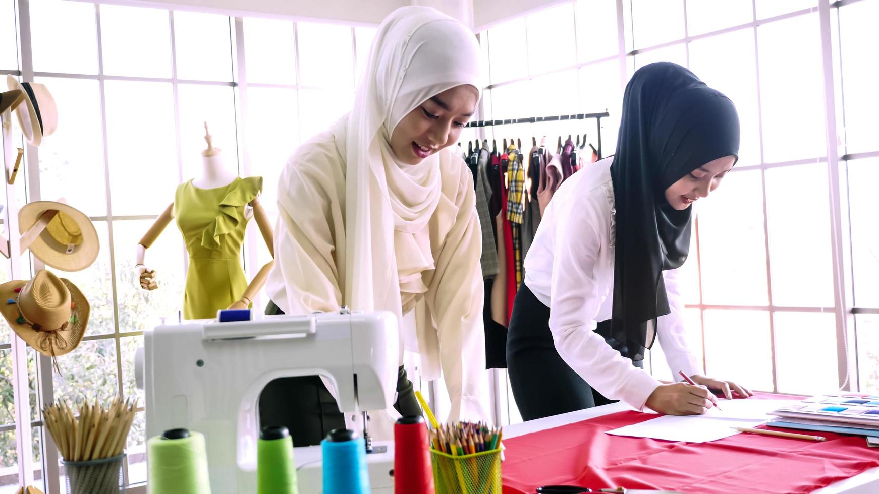 Schöne muslimische Frauen skizzieren zusammen Kleidersilhouetten im Büro. foto