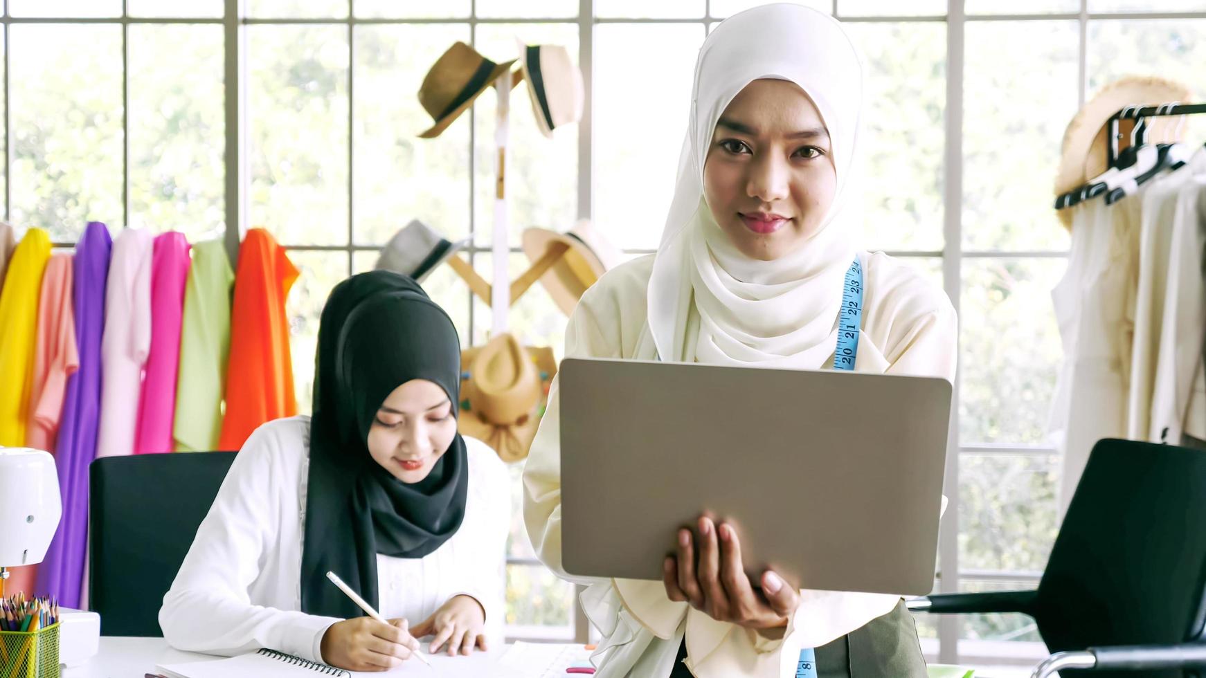 glückliche muslimische frauen, die im bekleidungsbüro zusammenarbeiten. foto