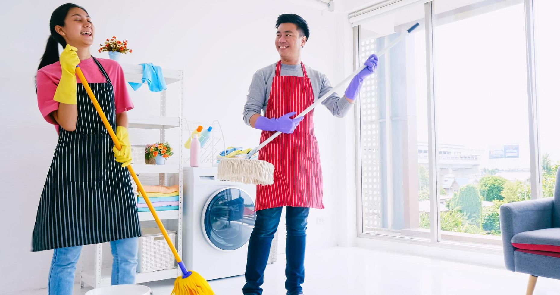 ehemann und frau haben spaß beim aufräumen ihres zimmers. glückliches asiatisches paar, das zeit zusammen zu hause verbringt. foto