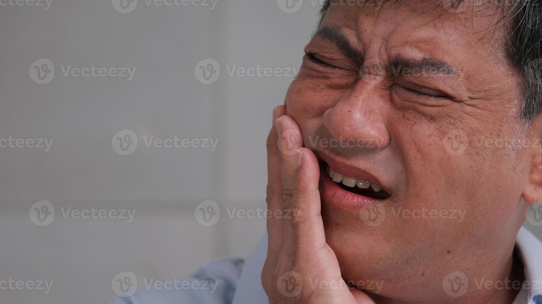 asiatischer älterer mann, der unter zahnschmerzen leidet. foto