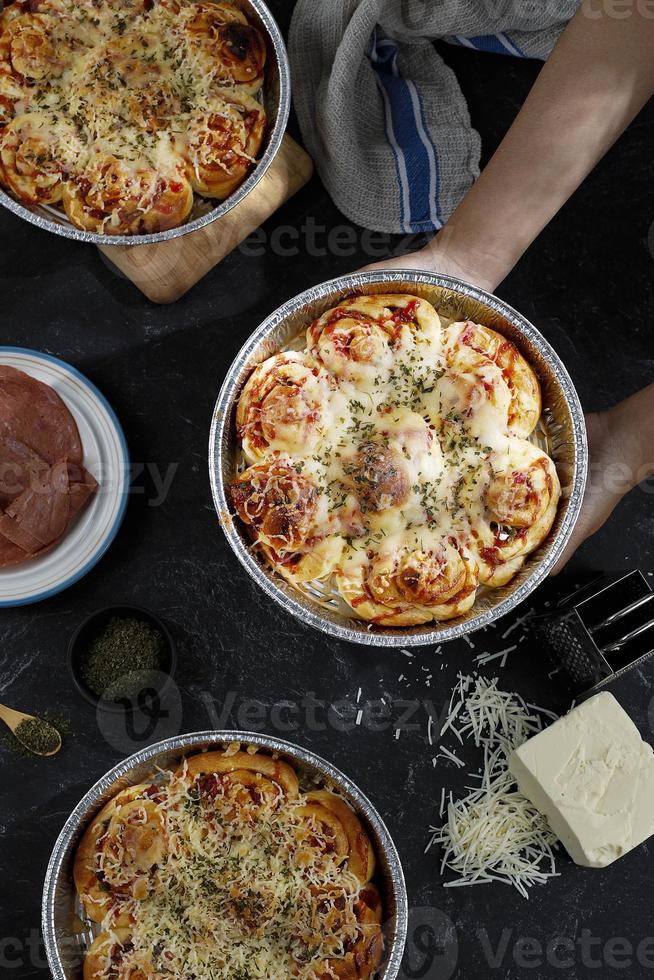 Pizzabrötchen mit geschmolzenem Käsebelag auf runder Alu-Backform foto