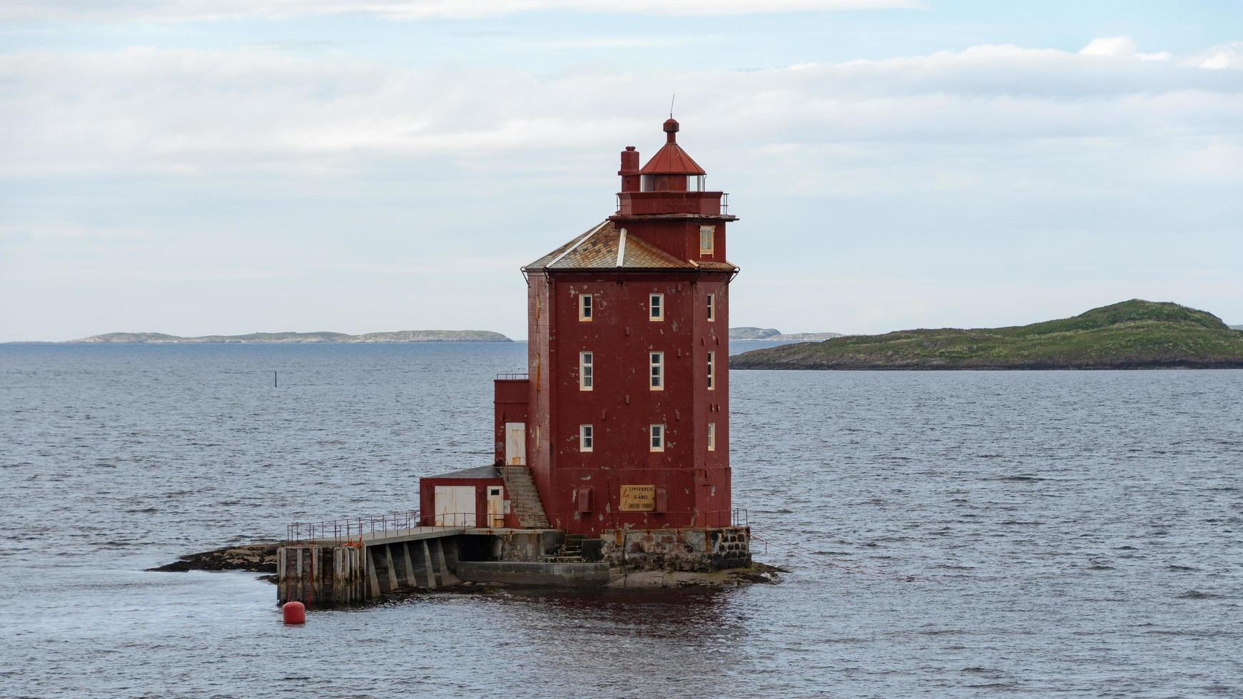 roter leuchtturm auf einer winzigen insel vor der küste norwegens. foto