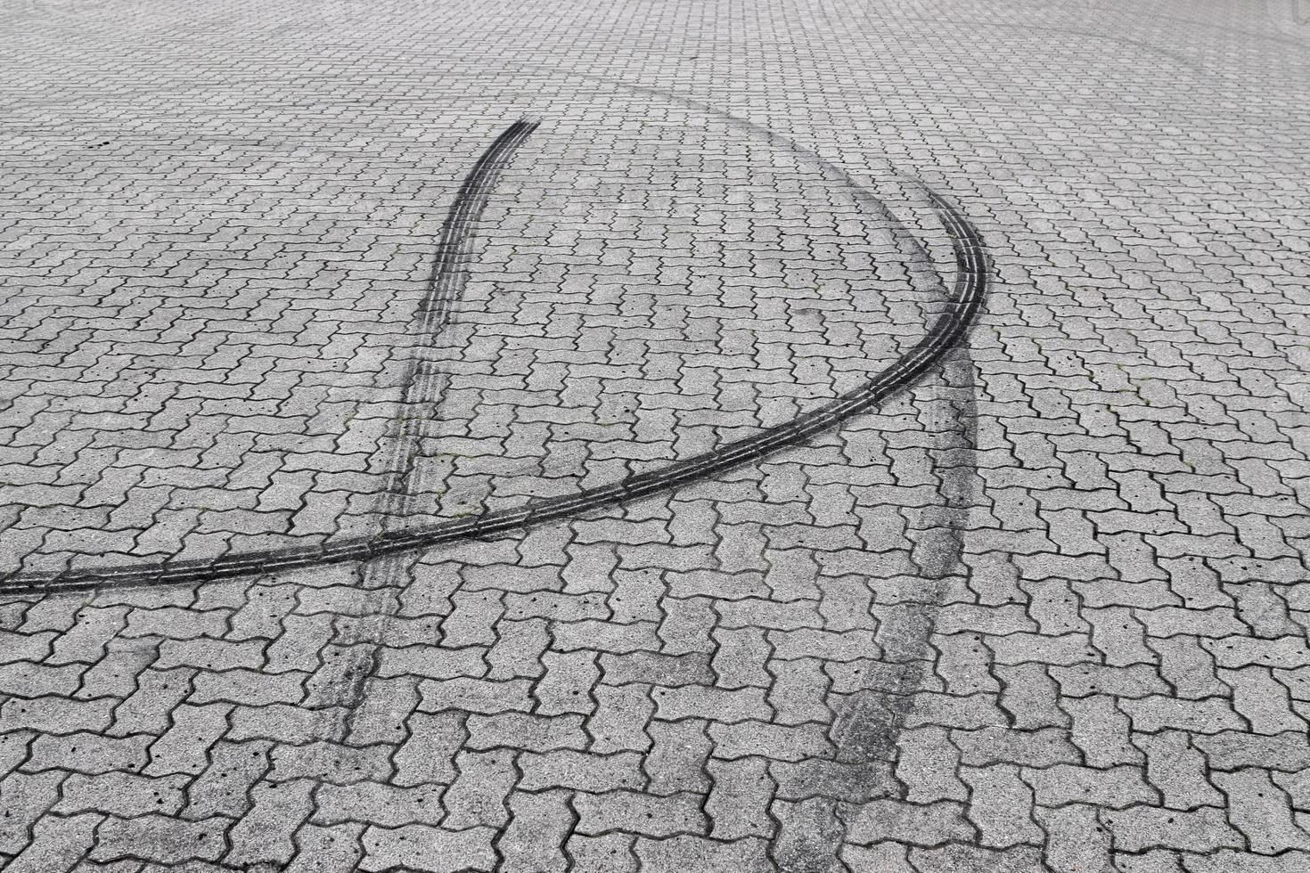 Schwarze Reifenspuren auf einer Kopfsteinpflasterstraße foto