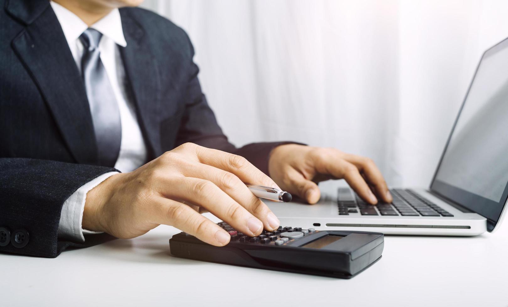 Geschäftsbuchhaltungskonzept, Geschäftsmann, der Taschenrechner mit Computerlaptop, Budget und Kreditpapier im Büro verwendet. foto