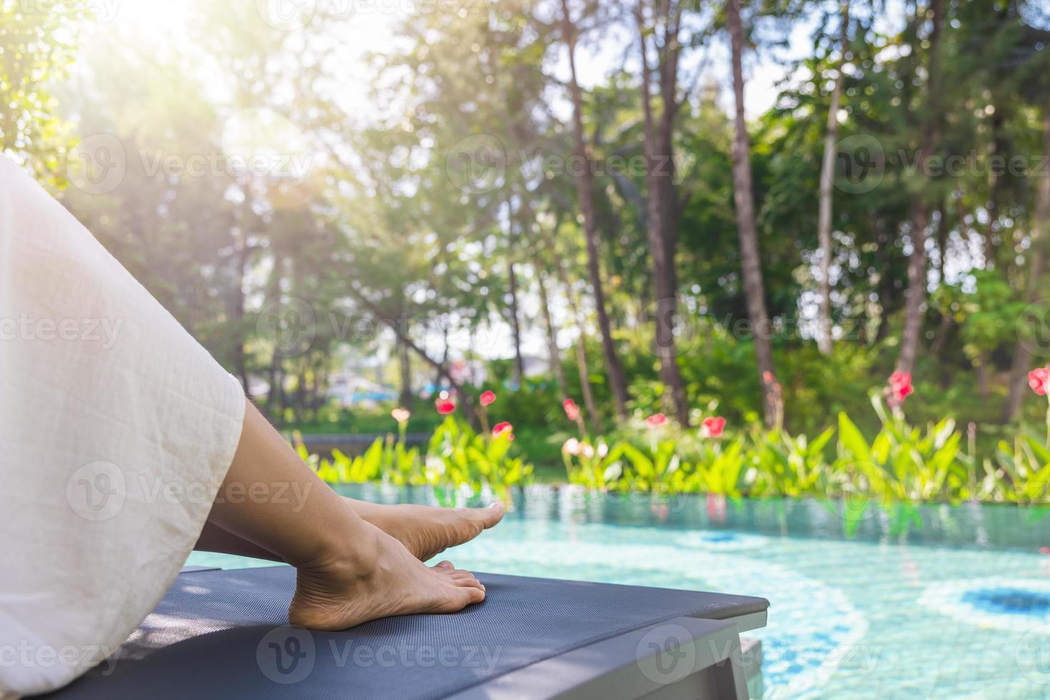 Schöne saubere Frauenfüße über Wasser im Schwimmbad. schönes und elegantes gepflegtes mädchen berührt ihren fuß. konzept über spa, reise und hautpflege foto