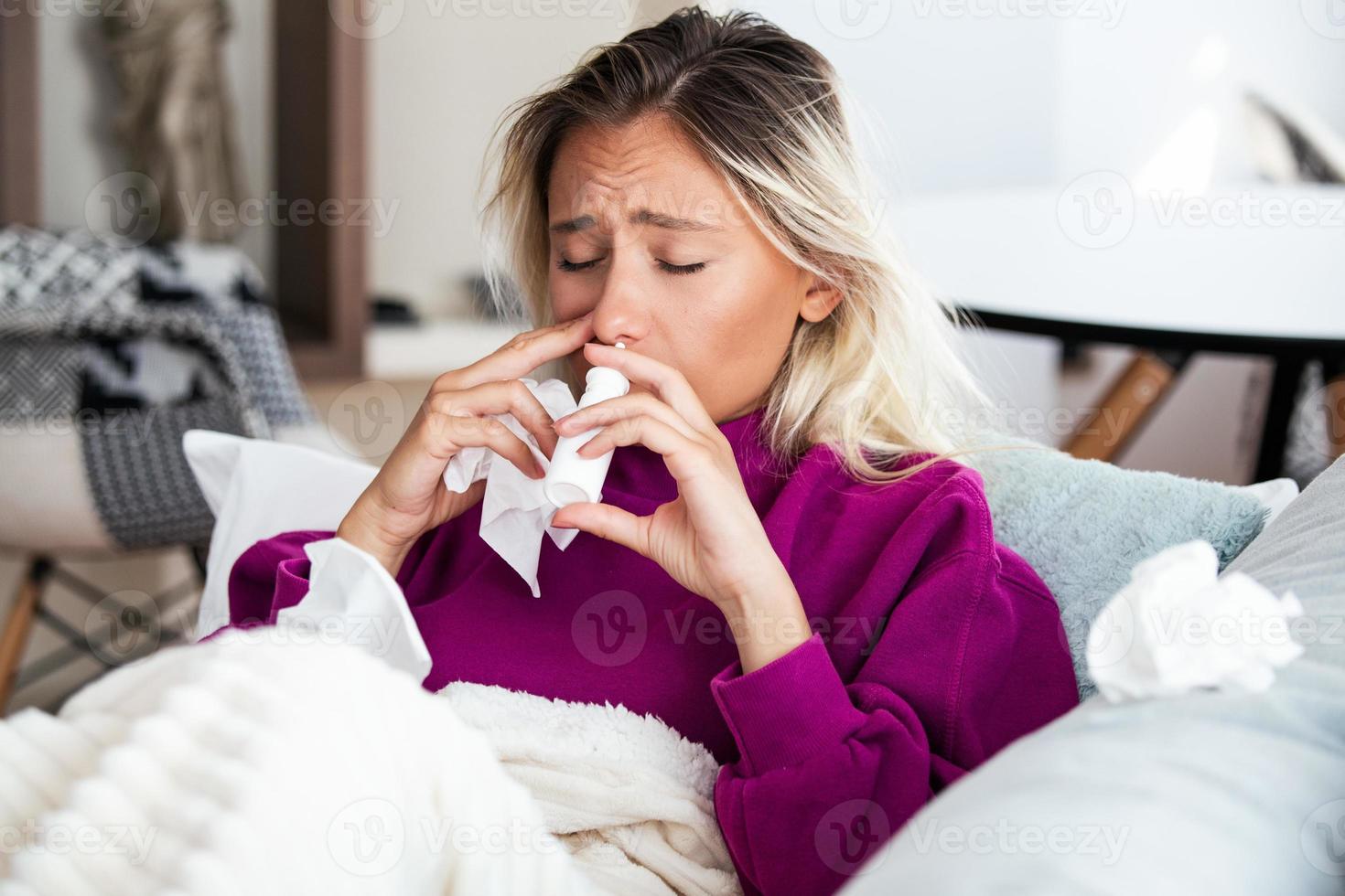 Frau hat Grippe und sie benutzt Nasenspray, um sich selbst zu helfen. Frau mit Nasenspray. Nasenspray gegen Erkältung. krank mit einer Rhinitis-Frau, die Nase tropft. Frau trägt Nasenspray auf foto