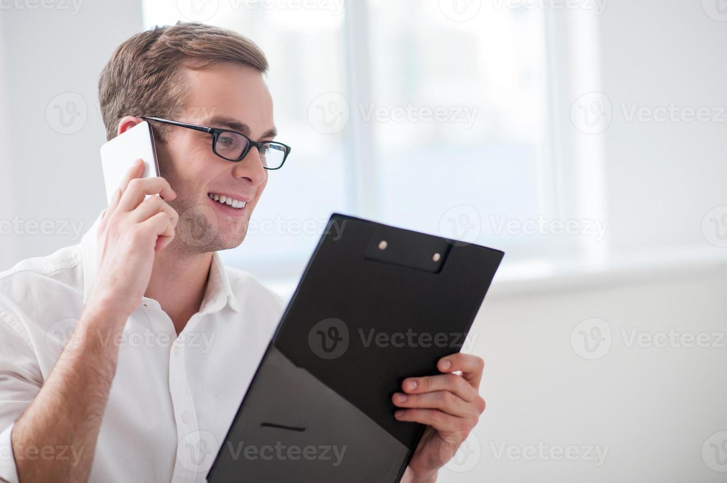 Der hübsche junge Geschäftsmann kommuniziert am Telefon foto