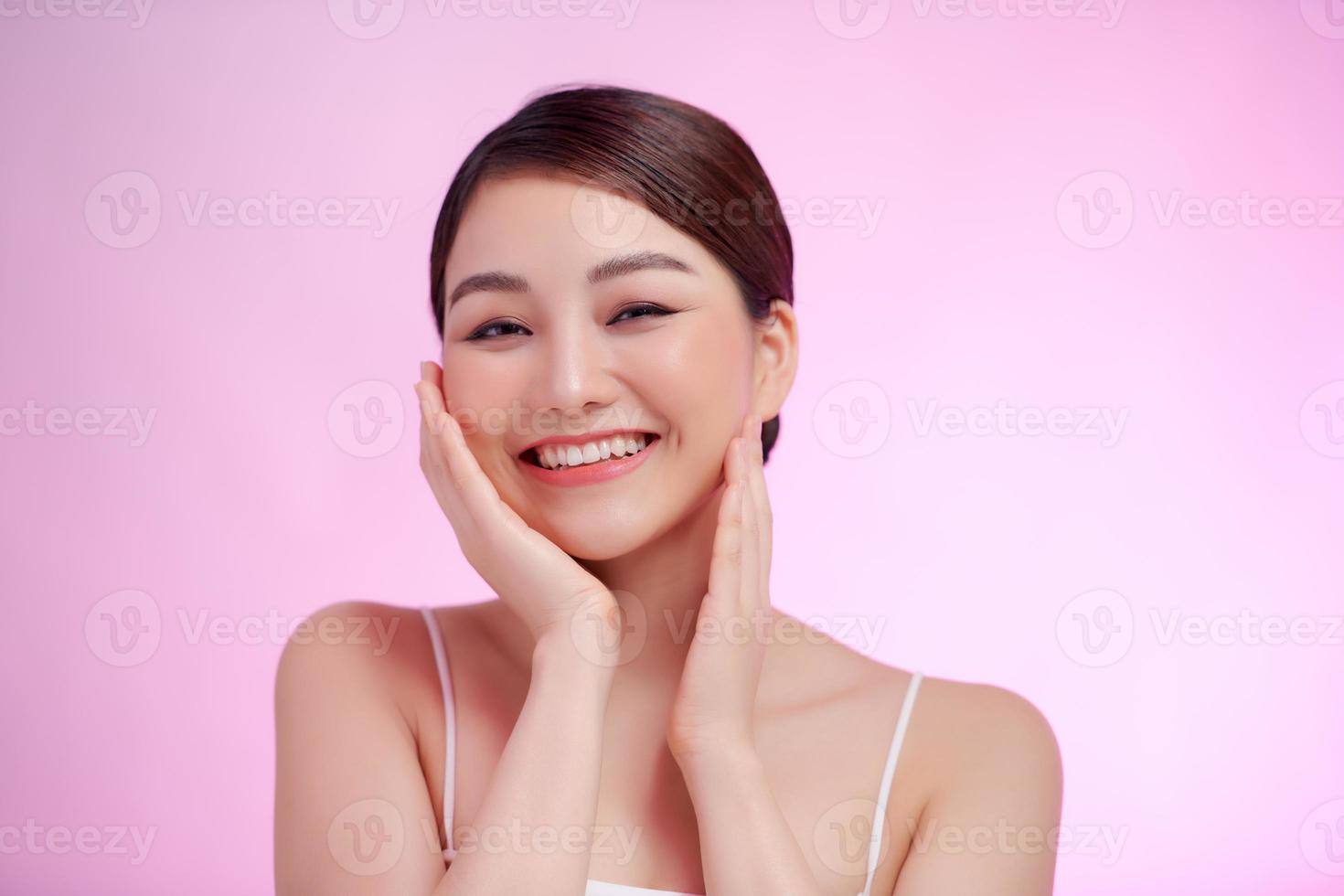 schöne asiatische frau, die ein weiches wangenlächeln mit sauberer und frischer haut mit positiven emotionalen auf weißem hintergrund berührt foto