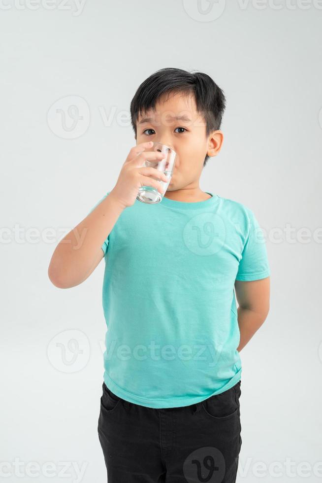 kleiner asiatischer junge, der tablettenmedizin mit einem glas wasser einnimmt. gesundheitswesen und medizinisches konzept. foto