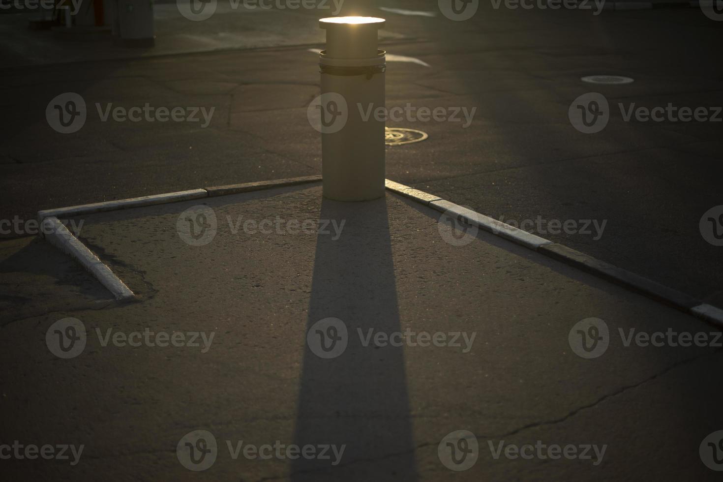 Urne auf dem Parkplatz. Ort, um Müll auf der Straße zu sammeln. Schatten vor Müll auf Asphalt. foto