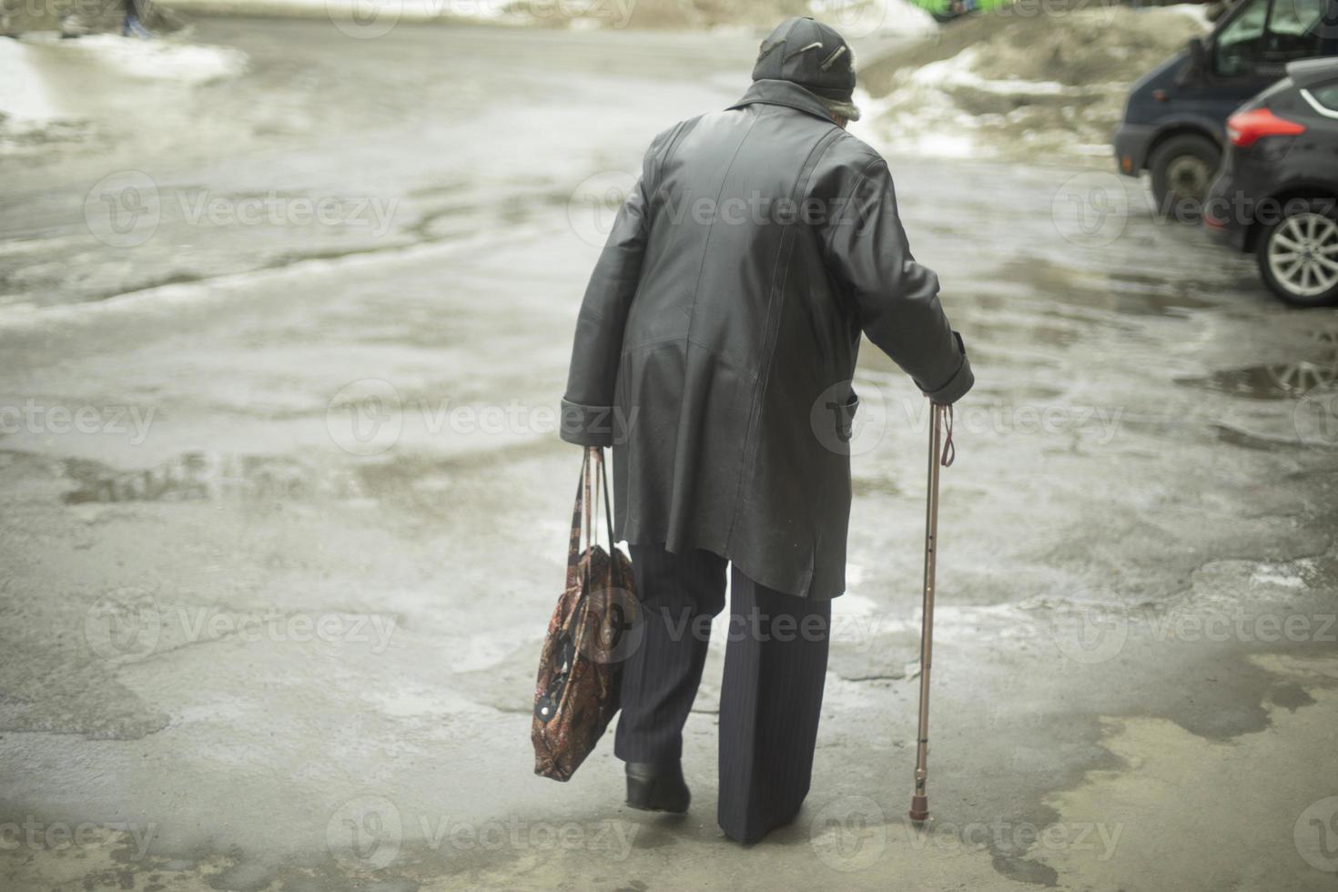 Frau mit Porenstab geht beim Gehen die Straße hinunter. Rentner in Russland. foto