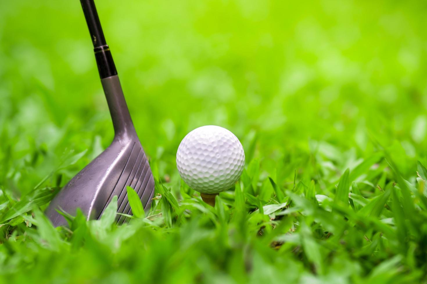 Golfschläger, der Golfball auf grünem Gras schlägt foto