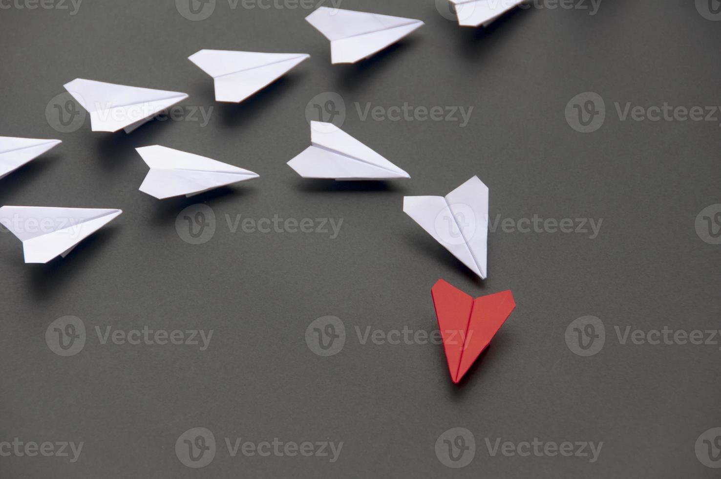 rotes papierflugzeug origami führende weiße flugzeuge auf dunklem hintergrund. konzept für führungskompetenzen foto