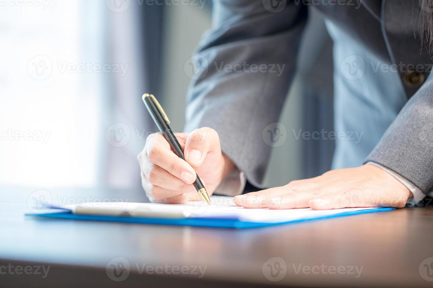 Arbeitsplatz Nahaufnahme Person professionelle Geschäftsfrau sitzt am Schreibtisch halten Stiftunterzeichnung oder Unterschrift Vertragspapier. angestellte frau, die vereinbarungsdokument auf papierkramformular schreibt, unternehmen im arbeitsbüro foto