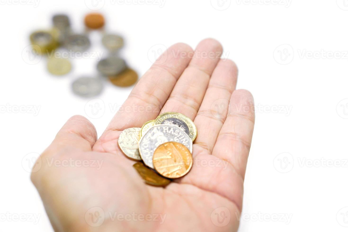 britische währungsmünzen zur hand und verschwommene münzen mit isolieren auf weißem hintergrund und mit pfaden machen. foto