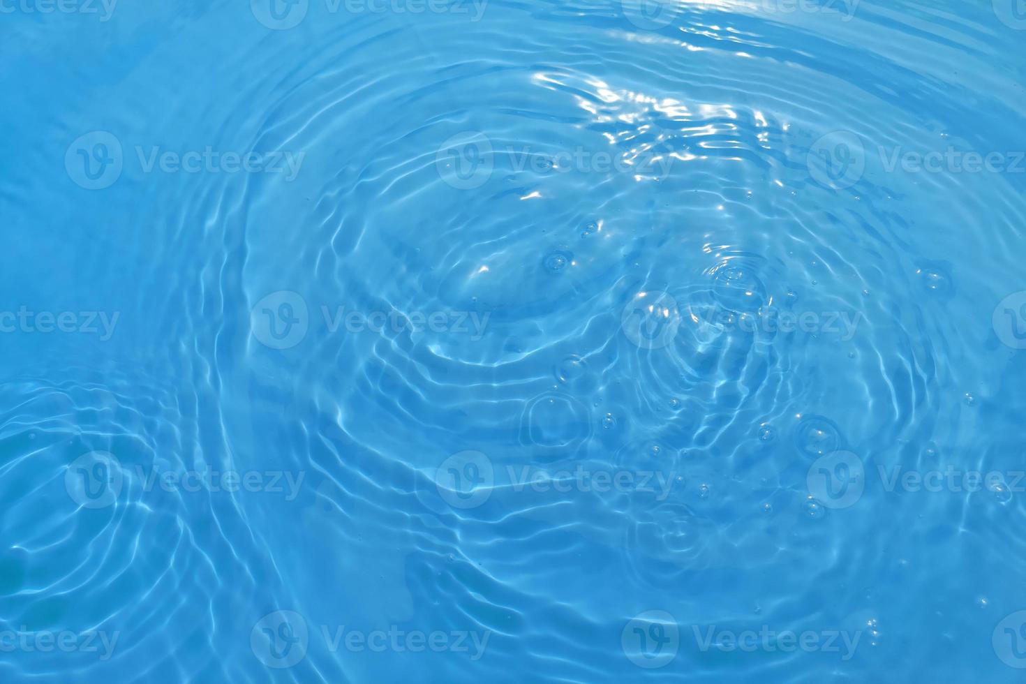 defocus verschwommene, transparente, blaue, klare, ruhige wasseroberflächenstruktur mit spritzern und blasen. trendiger abstrakter naturhintergrund. wasserwelle im sonnenlicht mit kopierraum. blaues aquarell glänzt. foto