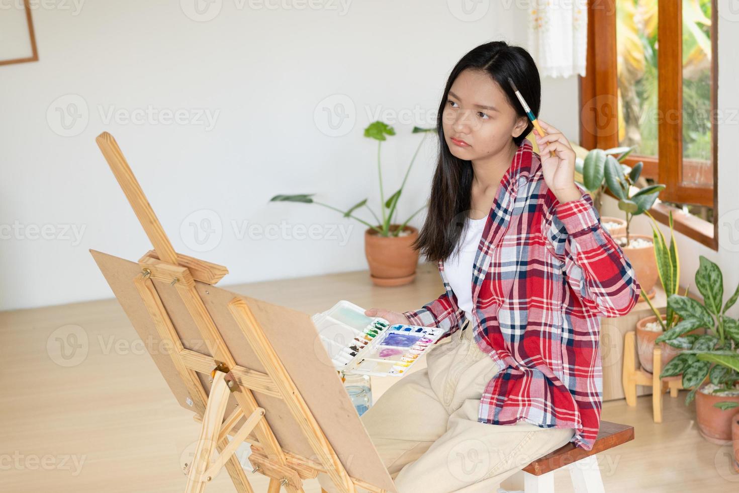 junges mädchen malt zu hause auf papier, holzrahmen, hobby und kunststudium zu hause. foto