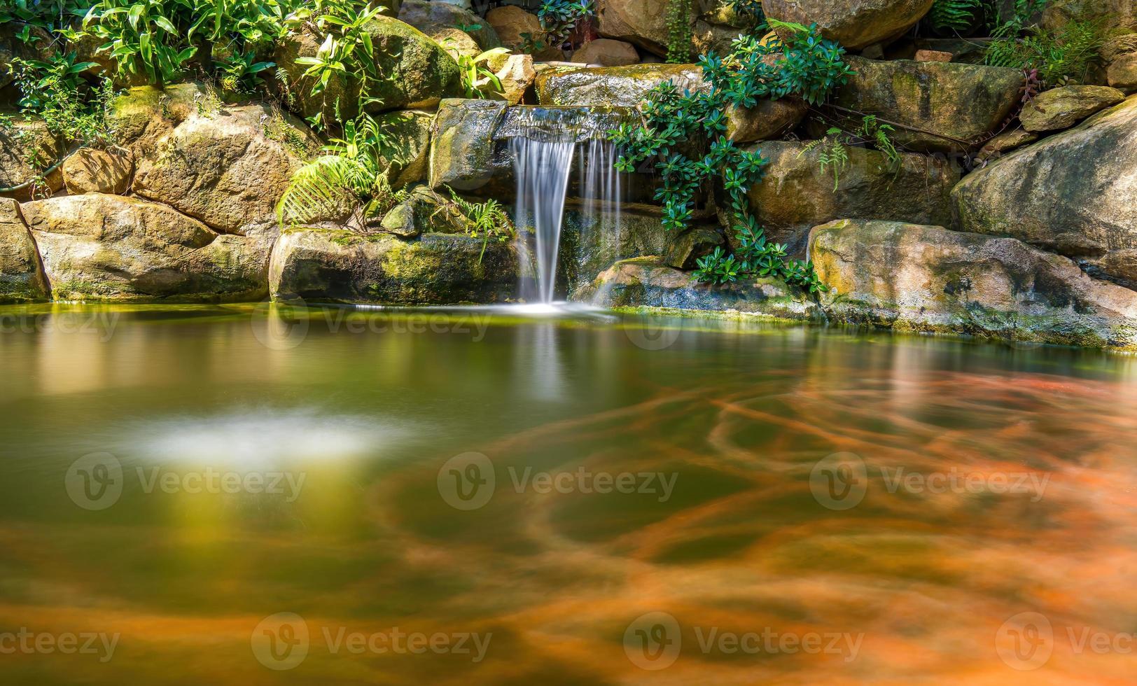 Wasserfälle im japanischen Garten. Üppig grüner tropischer Koi-Teich mit Wasserfall von jeder Seite. ein üppiger grüner Garten mit Wasserfall, der die felsigen Steine hinunterstürzt. Zen und friedlicher Hintergrund. foto