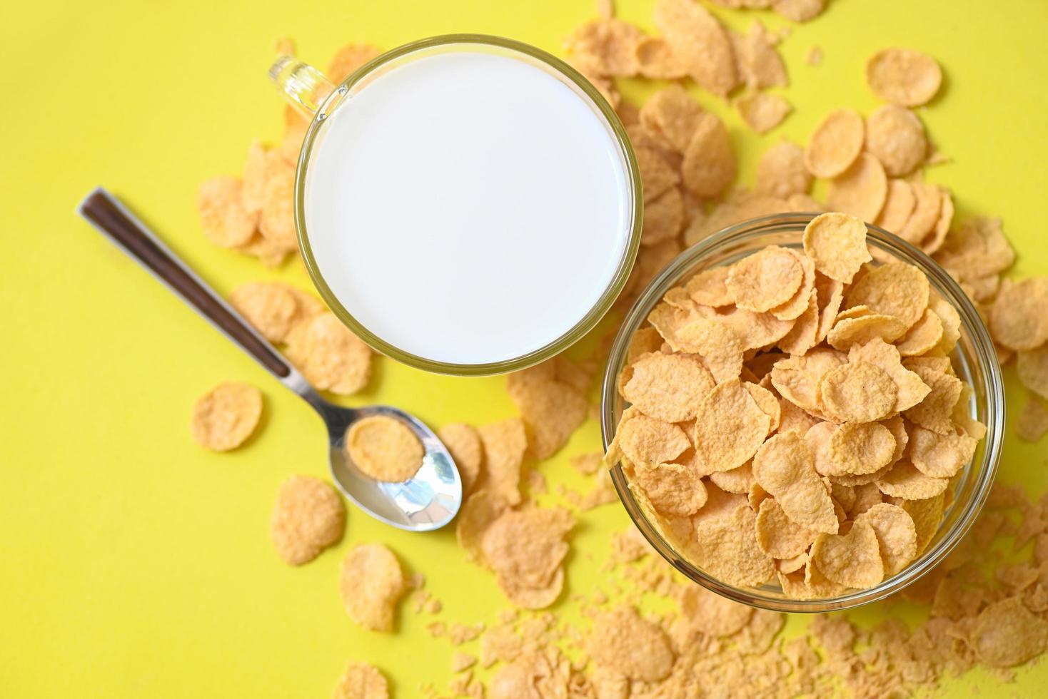 cornflakes schüssel frühstück und snack für ein gesundes lebensmittelkonzept, morgendliches frühstück frisches vollkornmüsli, cornflakes mit milch auf gelbem hintergrund - draufsicht foto