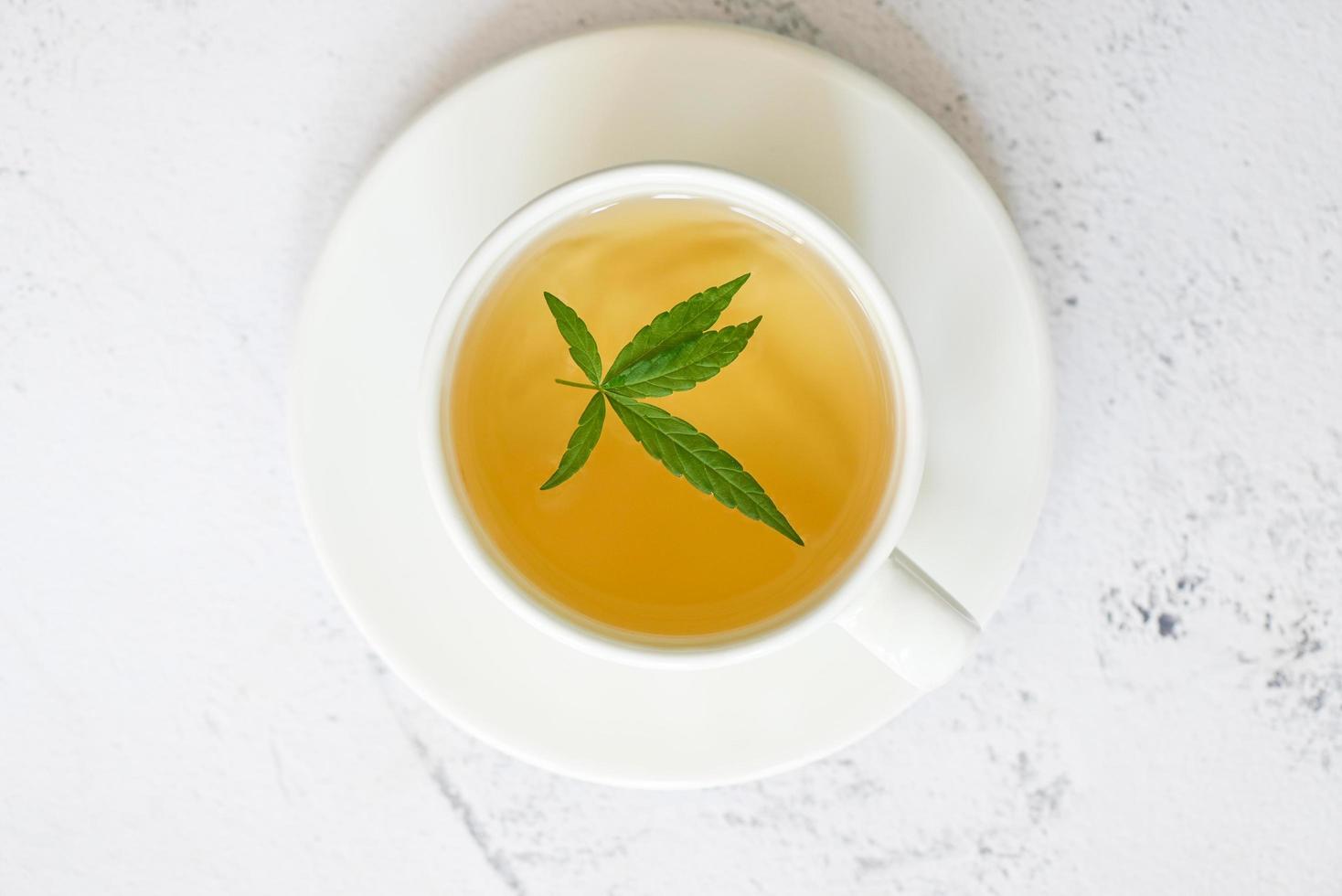 Cannabistee Kräuter auf Teetasse mit Cannabisblatt Marihuanablätter Kraut, Gesundheitstee mit Hanfblattpflanze thc cbd Kräuter Lebensmittel und Medizin foto