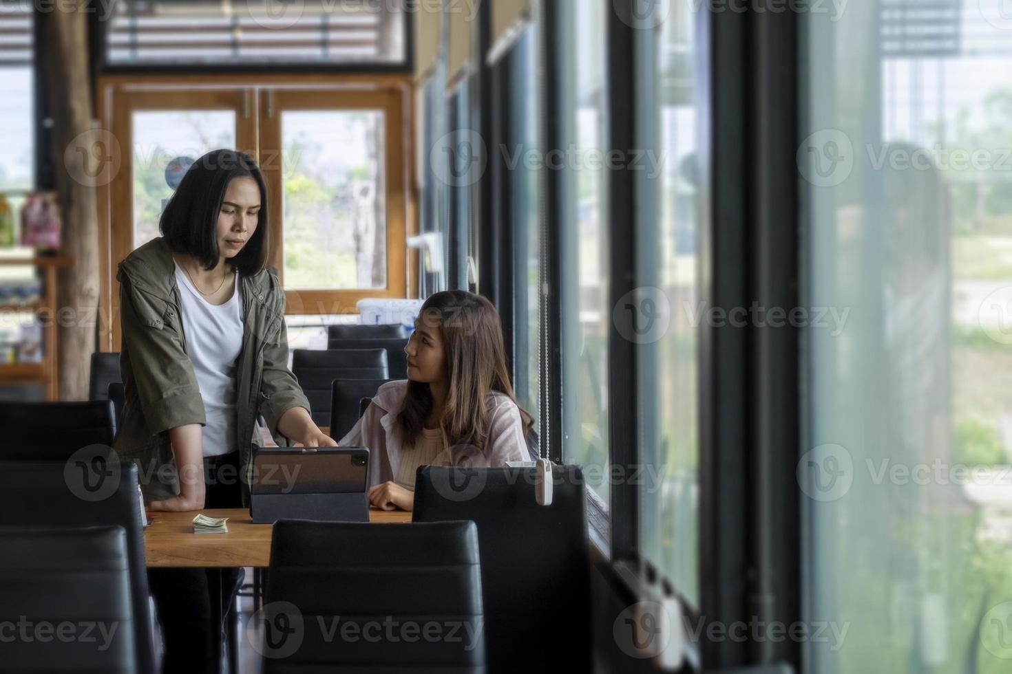 Zwei Frauen diskutieren über Geschäfte, während sie ein Tablet verwenden. an einem Tisch in einem Café foto