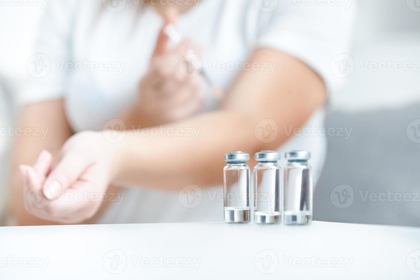 Glasflaschen mit Insulin gegen Frau, die Stich macht foto