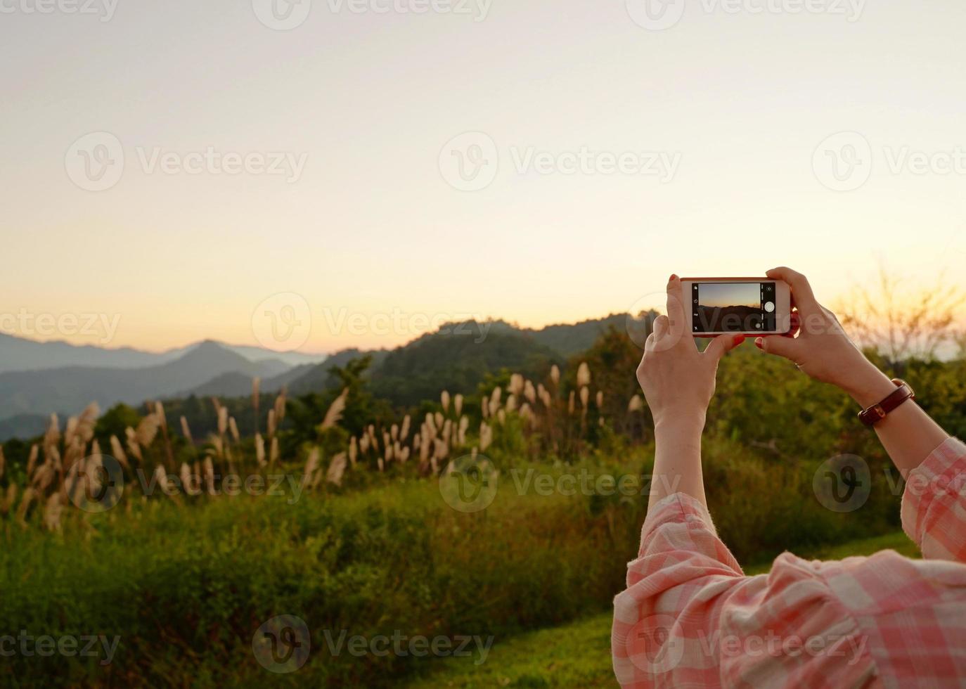junge asiatische frau, die ein foto mit ihrem telefon in der schönen bergansicht macht