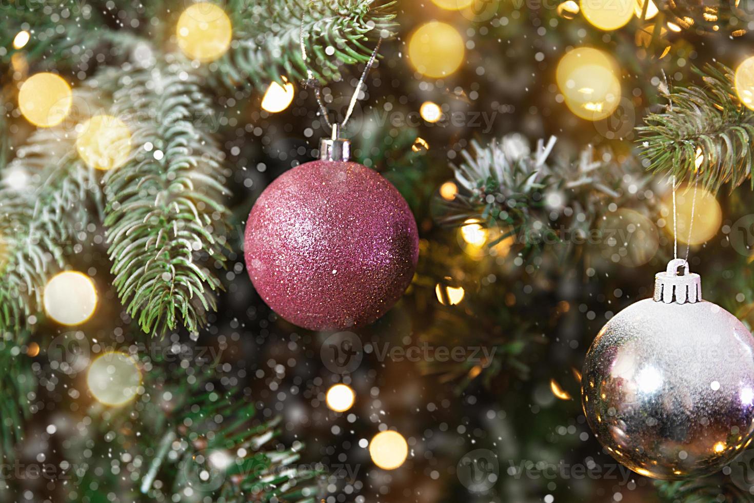 klassisches weihnachtsneujahr geschmückter neujahrsbaum mit rosa und weißen ornamentdekorationen spielzeug und ball, schnee und defokussierten girlandenlichtern. modernes klassisches Urlaubsdesign. Heiligabend zu Hause. foto