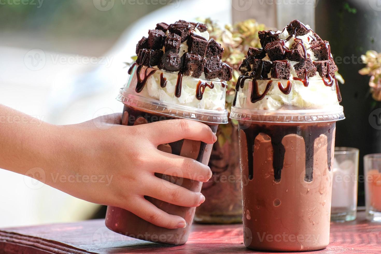 Hand mit einer Tasse Eiskakao, Kaffee, Kakao, Brownies, stilvollem Café foto