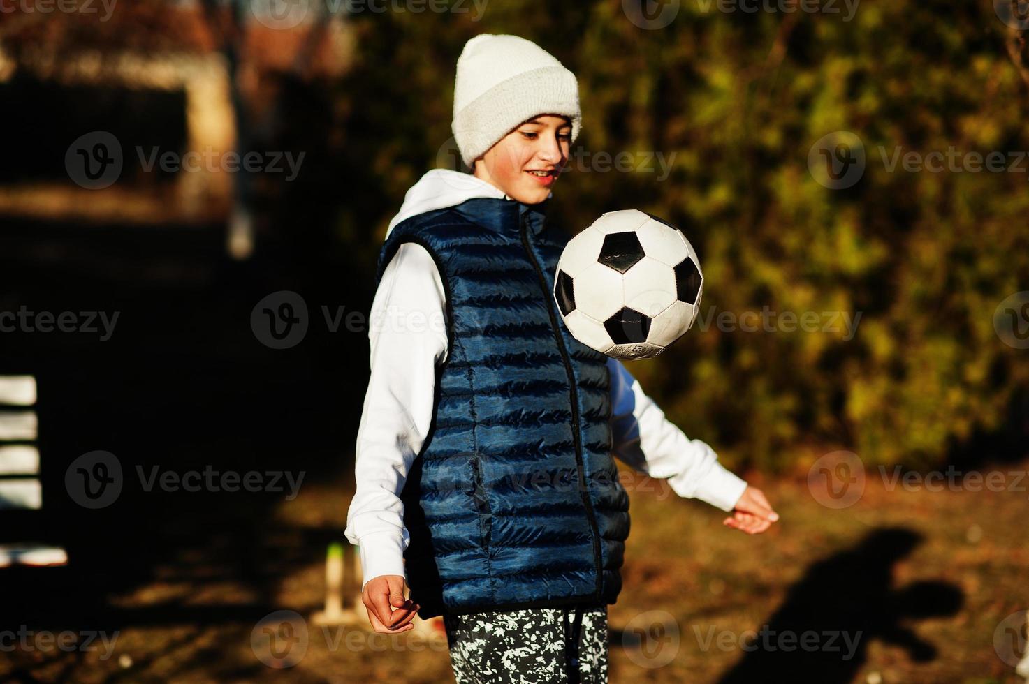 Junge spielt mit dem Fußball im sonnigen Frühlingstag. foto