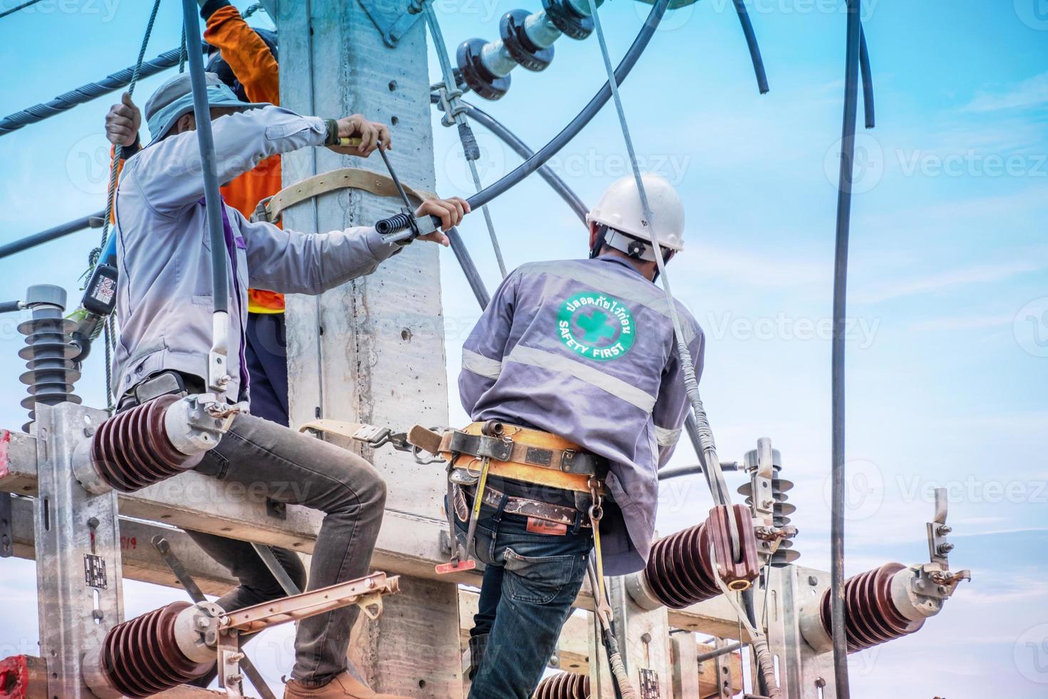 Elektriker klettern auf Strommasten, um Stromleitungen zu installieren und zu reparieren, einige Techniker tragen keine Helme. kann gefährlich sein foto