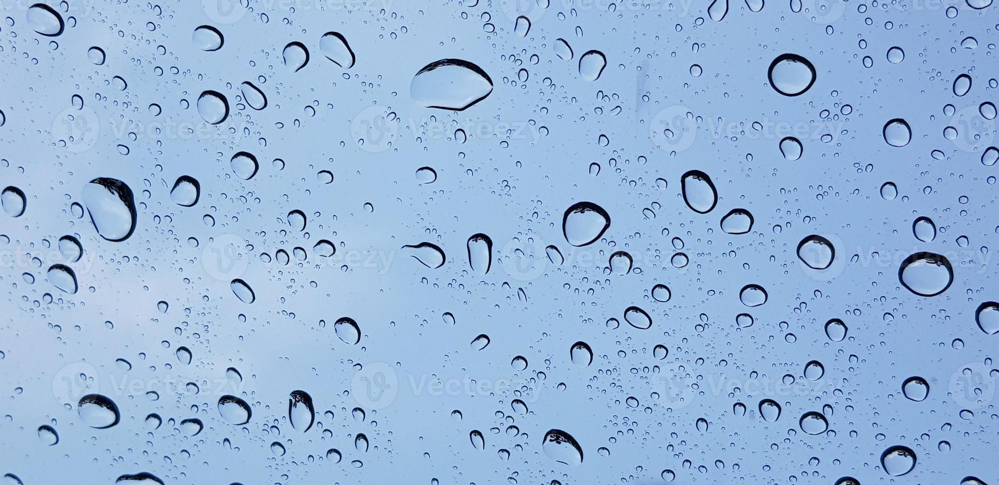 Perspektive der Wassertropfen durch die Fensterglasoberfläche gegen den blauen Himmel, gut für Multimedia-Inhalte foto