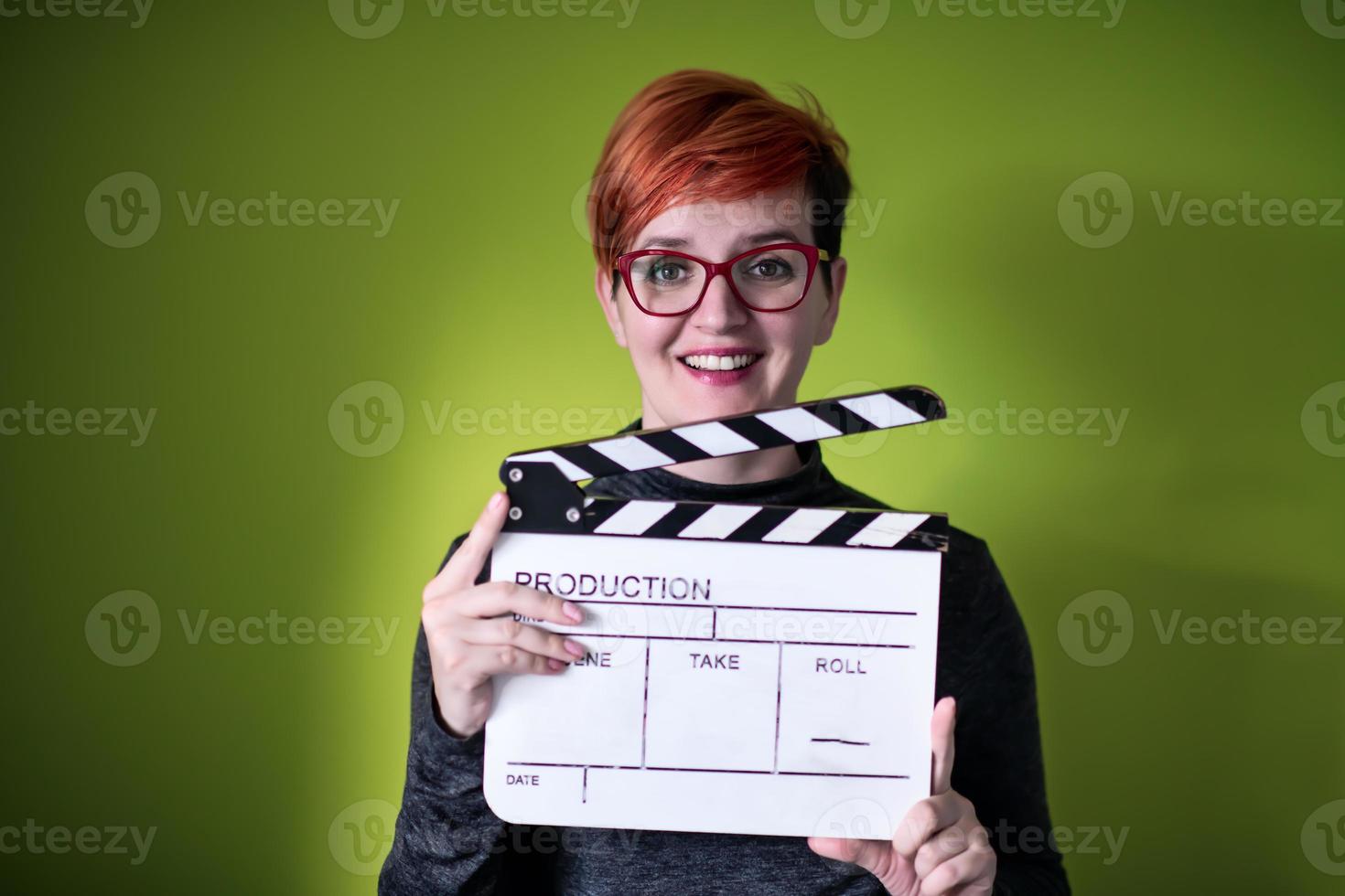 Frau mit Filmklöppel vor grünem Hintergrund foto