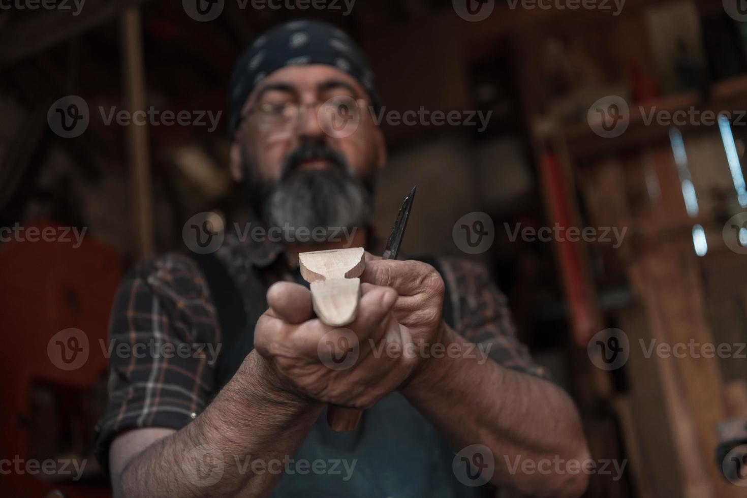 Löffelhandwerksmeister in seiner Werkstatt mit handgefertigten Holzprodukten und Werkzeugen arbeiten foto