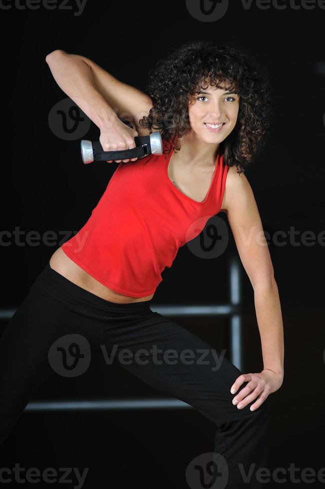 junge frau trainiert im fitnessclub mit hantel foto