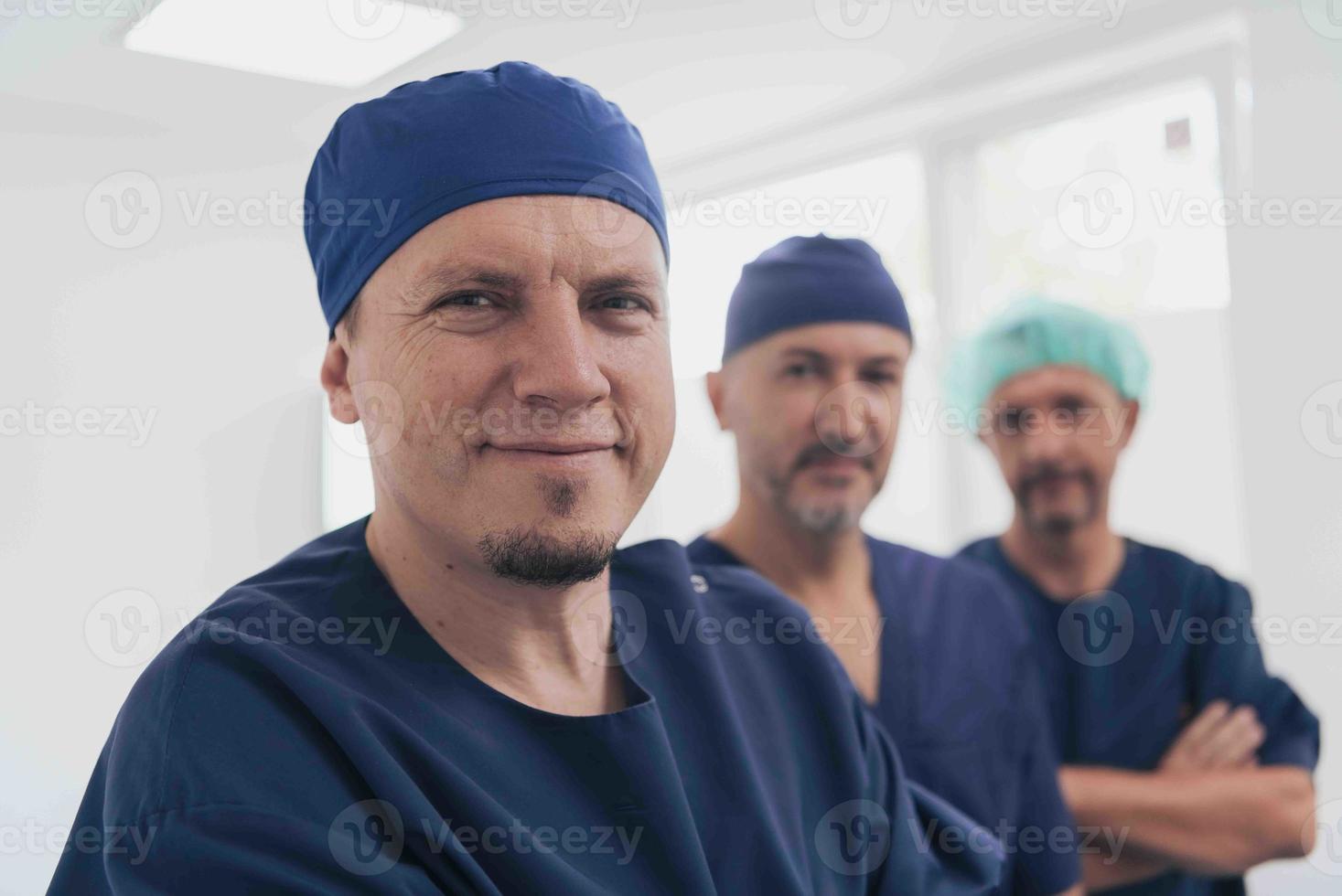 multiethnischer Orthopäde vor seinem medizinischen Team, der mit Gesichtsmaske in die Kamera schaut foto