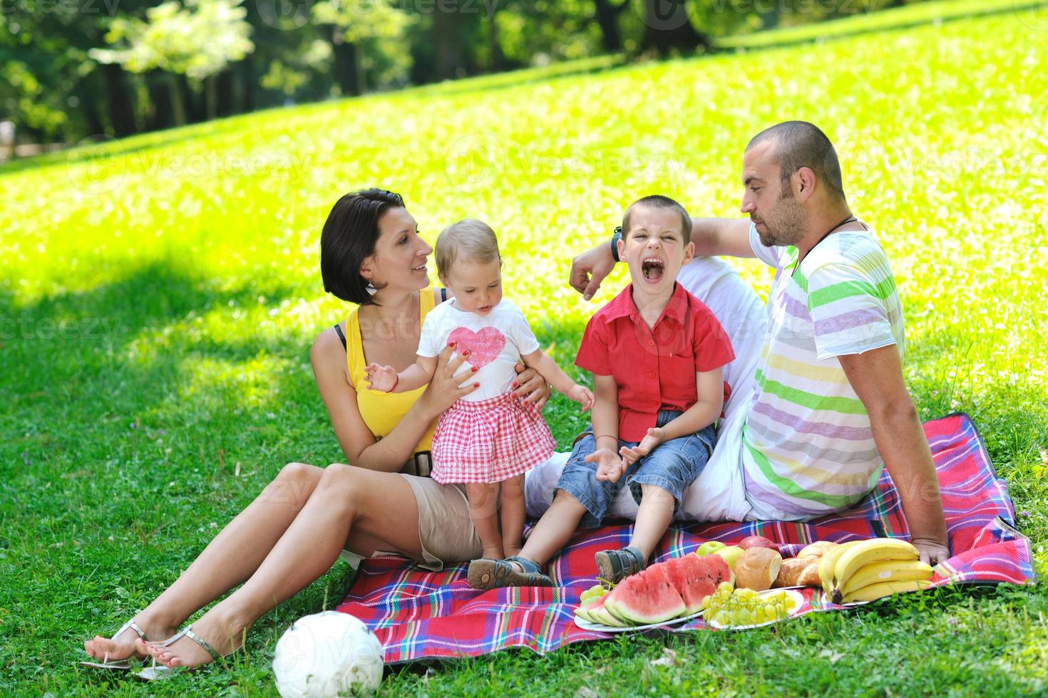 glückliches junges Paar mit ihren Kindern haben Spaß im Park foto