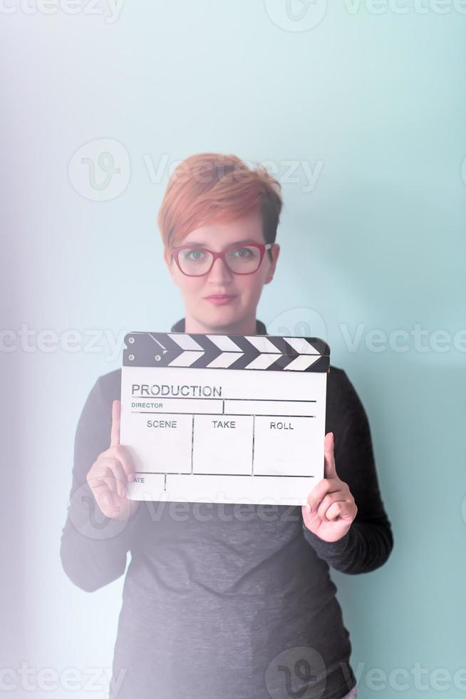 Frau mit Filmklöppel vor cyanfarbenem Hintergrund foto