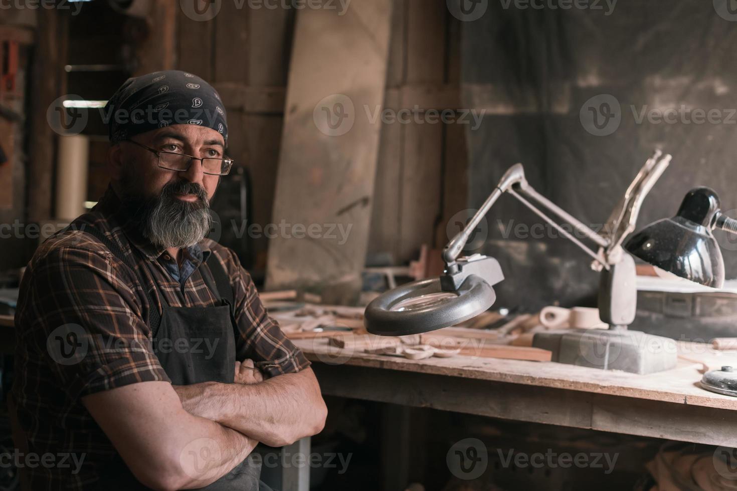 Löffelmeister in seiner Werkstatt mit Holzprodukten und Werkzeugen foto