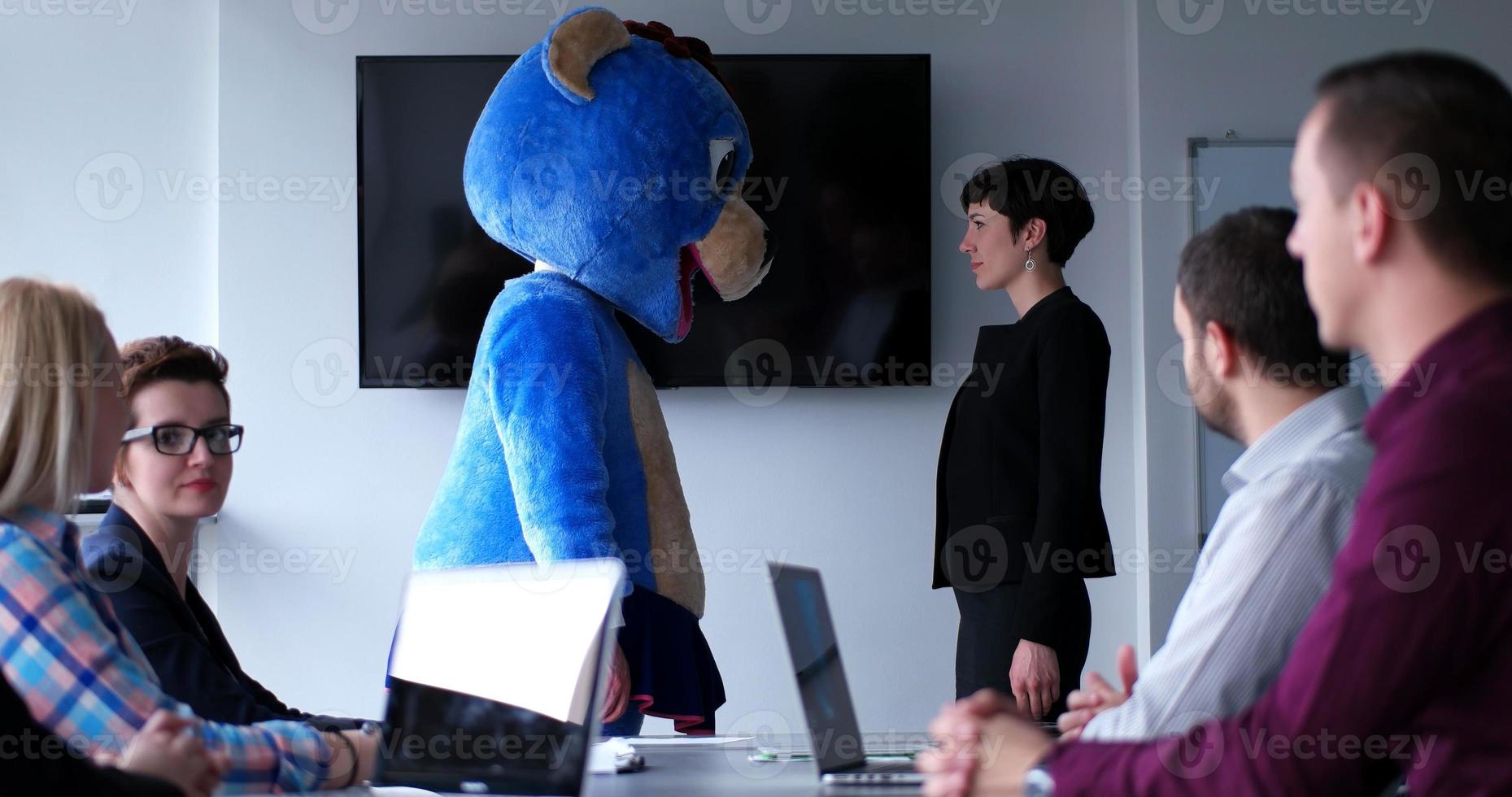 als bär verkleideter chef hat spaß mit geschäftsleuten im trendigen büro foto