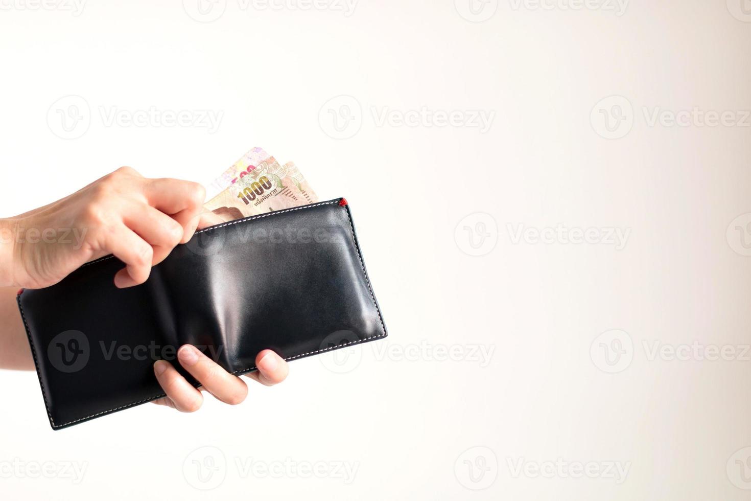 Hände halten eine Brieftasche mit thailändischen Banknoten von 1000 und 500 Baht. foto