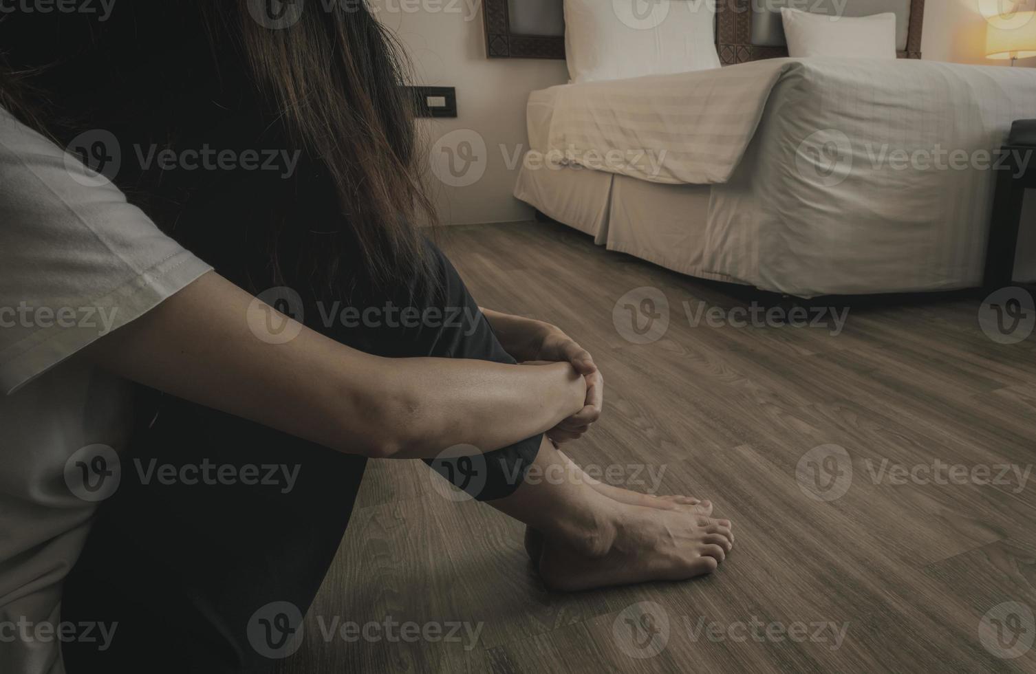 Depressive und gestresste Frau, die auf Vinylfliesen neben dem Bett im Hotelzimmer sitzt. traurige frau, die im schlafzimmer sitzt. Mädchen mit psychischen Problemen. unglückliches Leben. Konzept des Welttages der psychischen Gesundheit. foto