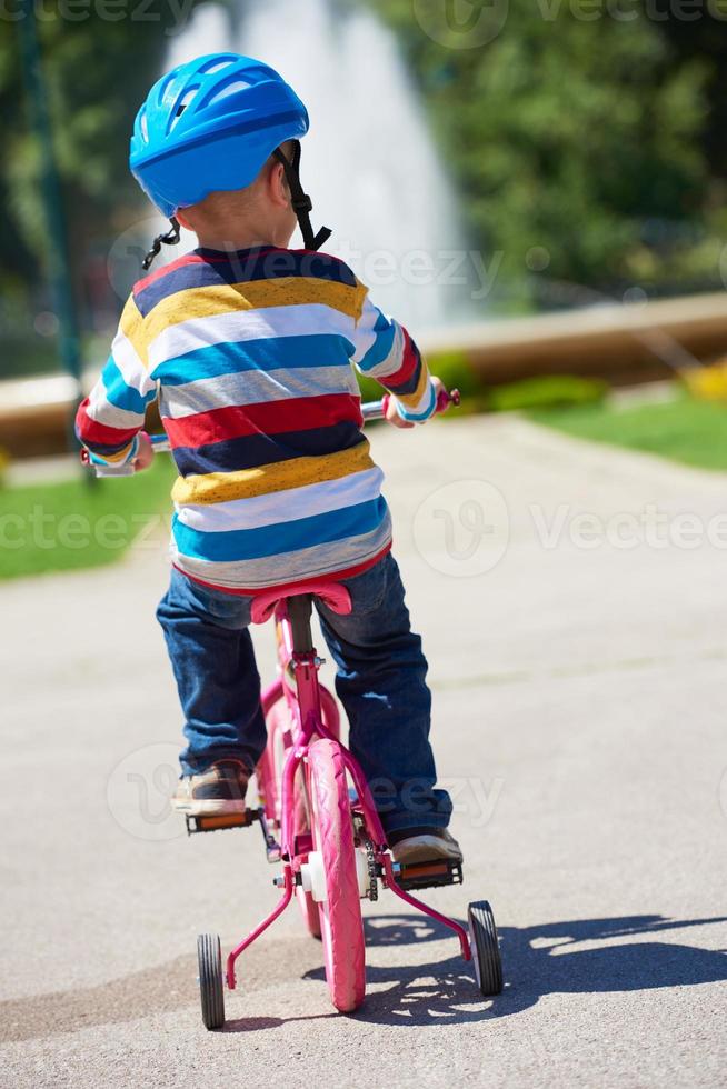 glücklicher junge, der lernt, sein erstes fahrrad zu fahren foto